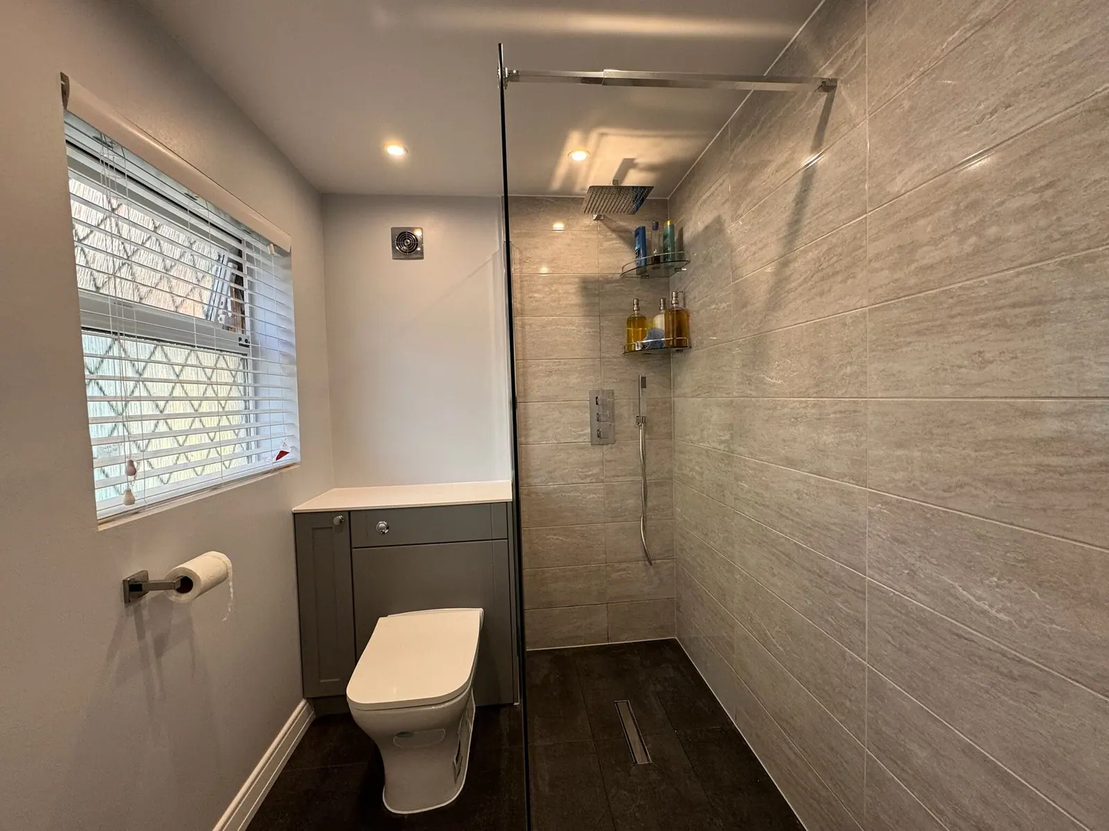 Shower room with a grey shaker vanity unit, walk-in shower behind a glass screen and dark slate-effect floor, fitted by Basingstoke Bathrooms